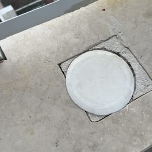 פתח ניקוז עגול במרפסת עם סימני חלודה