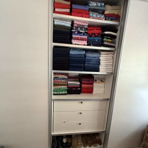 ארון בגדים מסודר עם בגדים מקופלים ונעליים בתחתית