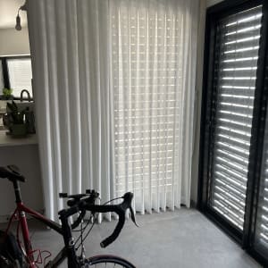 וילון לבן תלוי על חלון גדול בחדר מואר