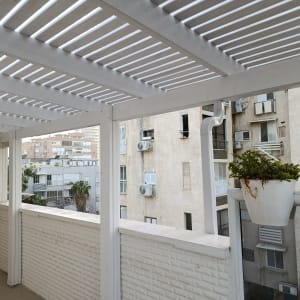 פרגולה לבנה במרפסת עם עציצים