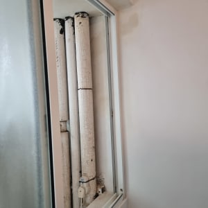 צינורות ישנים עם צבע מתקלף ליד חלון