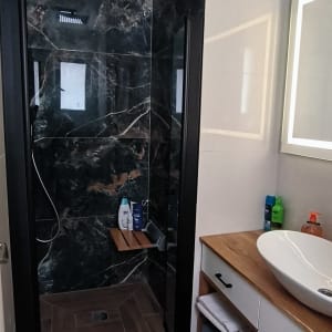 מקלחון עם קירות שיש כהה וראש מקלחת מרובע