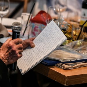 אדם מחזיק מיקרופון ומחברת עם כתב יד