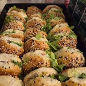 מגש אירוח עם כריכוני ביס מגוונים בלחמניות שומשום וקצח