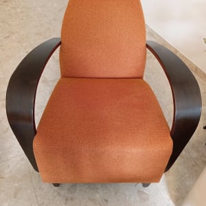 כורסה מרופדת בבד כתום עם ידיות עץ כהות