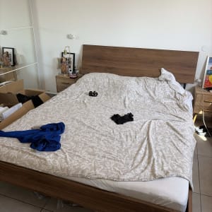 חדר שינה עם מיטה מסודרת וארגזים בצד