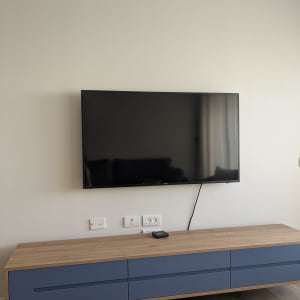 טלוויזיה תלויה על קיר עם שידה מתחת