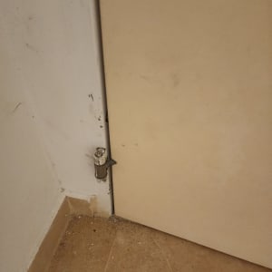 דלת עם ציר פגום על רצפה מלוכלכת