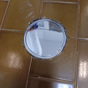 פתח ניקוז עגול ברצפת אריחים חומים