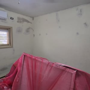 חדר עם קירות מוכנים לצביעה, כיסוי מגן ורוד על רהיטים