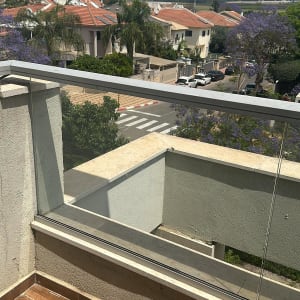 מעקה זכוכית במרפסת עם נוף עירוני