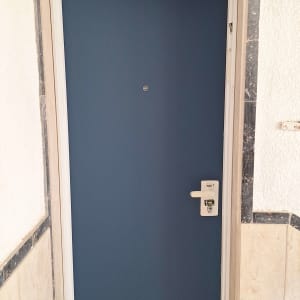 דלת כחולה עם ידית לבנה במסגרת שיש