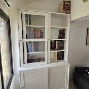 ארון ספרים לבן עם דלתות זכוכית וספרים בפנים