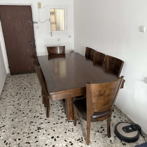 שואב אבק רובוטי ליד שולחן עץ וכיסאות