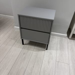 ארונית אפורה עם שתי מגירות על רצפת עץ