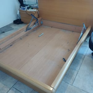 מיטה מעץ מפורקת עם חלקי מתכת על הרצפה