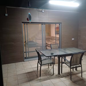 מרפסת עם שולחן זכוכית וכיסאות, תאורה עליונה