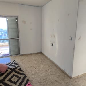 חדר עם קירות צבועים וכלי עבודה לצביעה על הרצפה