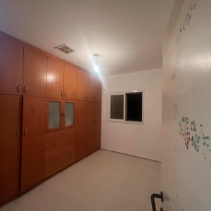 קיר עם סימני צבע וארון עץ בחדר ריק