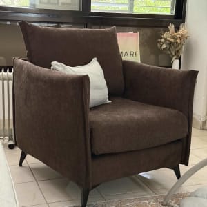 כורסה חומה עם כרית לבנה בחדר מואר