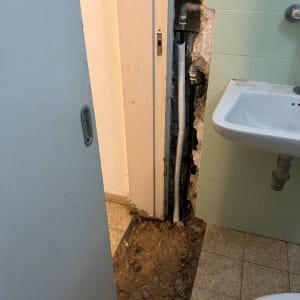 צינורות חשופים בקיר חדר אמבטיה עם עבודות תיקון