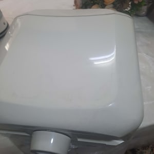 מיכל מים לבן על שולחן עם פרחים ברקע