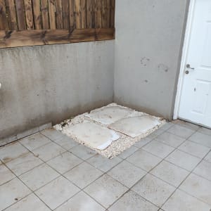 אבנים לבנות ואריחים בגינה קטנה ליד גדר עץ