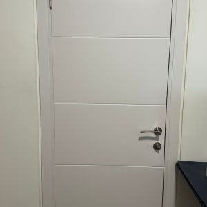 דלת לבנה עם ידית כסופה על קיר לבן