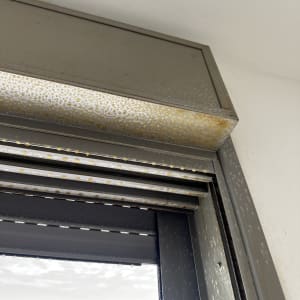 מסגרת חלון מתכתית עם כתמי חלודה ולכלוך