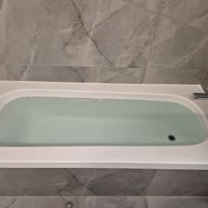 אמבטיה עם חיפוי קיר שיש וברז מתכת