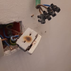 שקע חשמלי שרוף עם חוטים חשופים בקיר