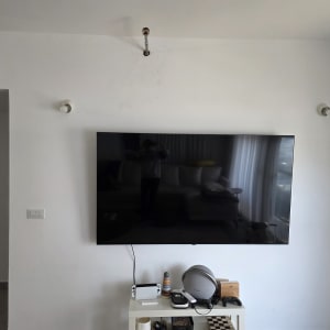 טלוויזיה תלויה על קיר עם שולחן קטן מתחת