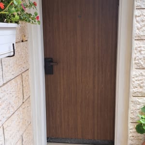 דלת עץ חומה עם ידית שחורה במסגרת לבנה