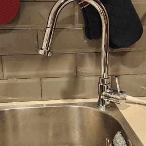 ברז נירוסטה מעל כיור מטבח עם ספוג קרצוף