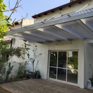 פרגולה מאלומיניום מחוברת לקיר חיצוני של בית