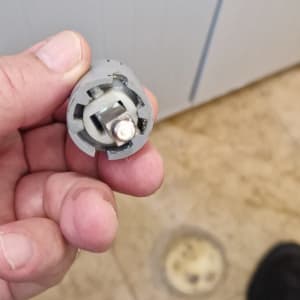 חלק פלסטיק קטן מוחזק ביד, רקע של רצפת חדר אמבטיה