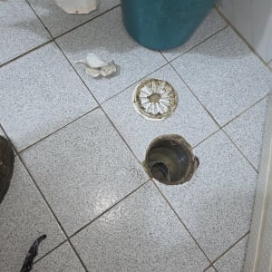 פתח ניקוז ברצפה עם מכסה פתוח וכלי עבודה