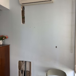 מזגן מותקן על קיר עם חור פתוח מתחתיו