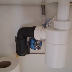 צנרת מתחת לכיור עם מחבר פלסטיק ולחצן