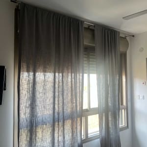 וילון אפור תלוי על מסילה מעל חלון