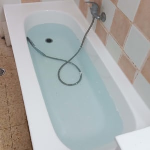 אמבטיה עם מים, אריחים בצבעים שונים על הקיר