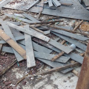 אדם עובד על תיקון רצפת עץ עם כלים