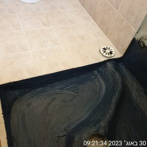 איטום רצפה עם חומר שחור סביב ניקוז