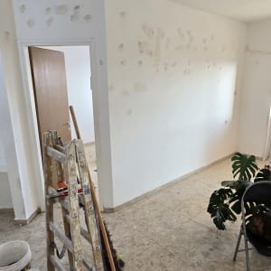 סולם וכלי צביעה בחדר עם קירות מוכנים לצביעה