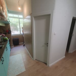 דלת לבנה עם ידית כסופה במסדרון צר