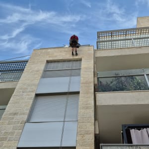 אדם על חבל מבצע איטום קיר חיצוני