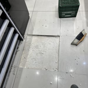 רצפה עם אריח שבור, מטאטא וארגז פלסטיק ירוק