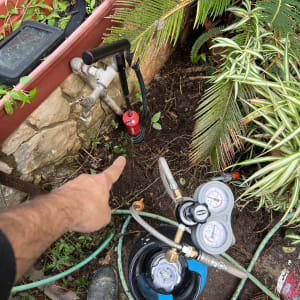 מד לחץ מחובר לצינור ליד ברז בגינה