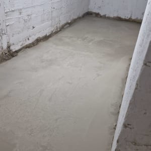 רצפת בטון חלקה בחדר עם קירות לבנים