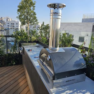 תנור חיצוני עם ארובה על משטח עץ בגינה